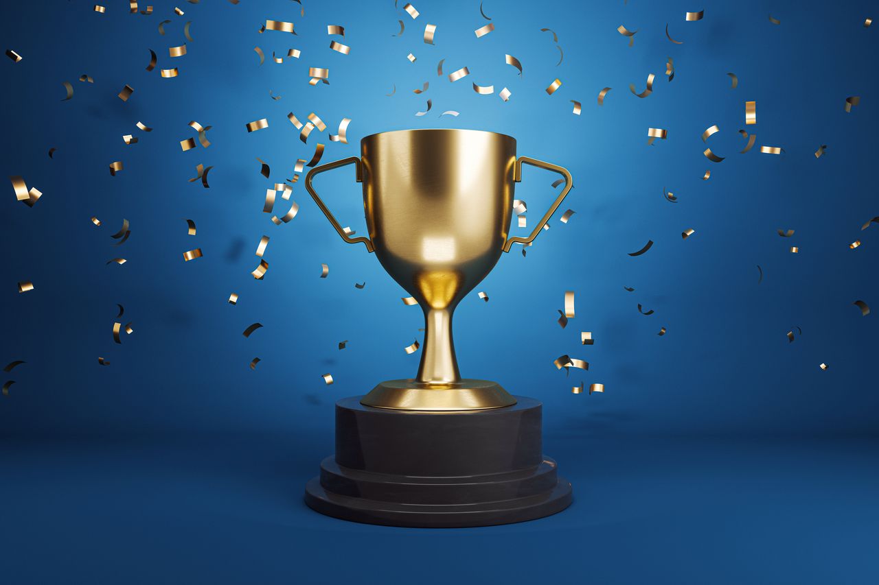 gold trophy surrounded by tiny gold confetti and blue background