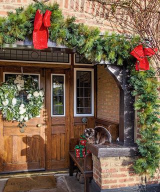 festive front porch with evergreen branches and red ribbons