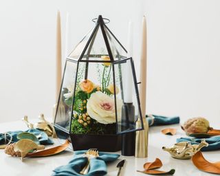 Terrarium thanksgiving centerpiece on wooden table with blue napkins and turkey candleholders