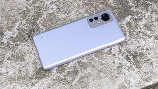 Un Xiaomi 12 tumbado boca abajo sobre una superficie de piedra. 