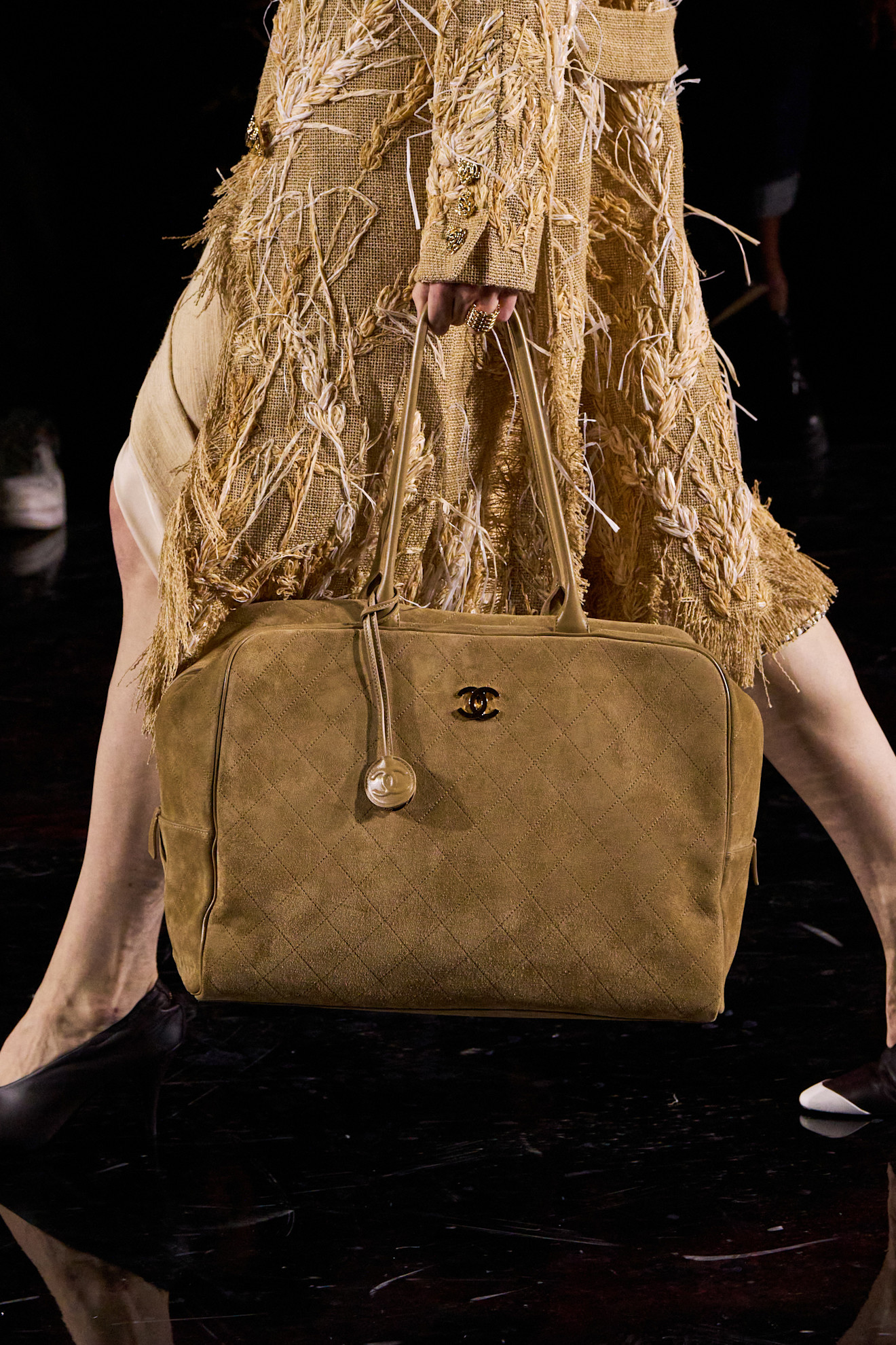 Model on the runway carrying a Chanel suede bag.