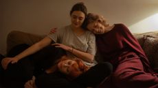 Three woman sit embraced on a couch