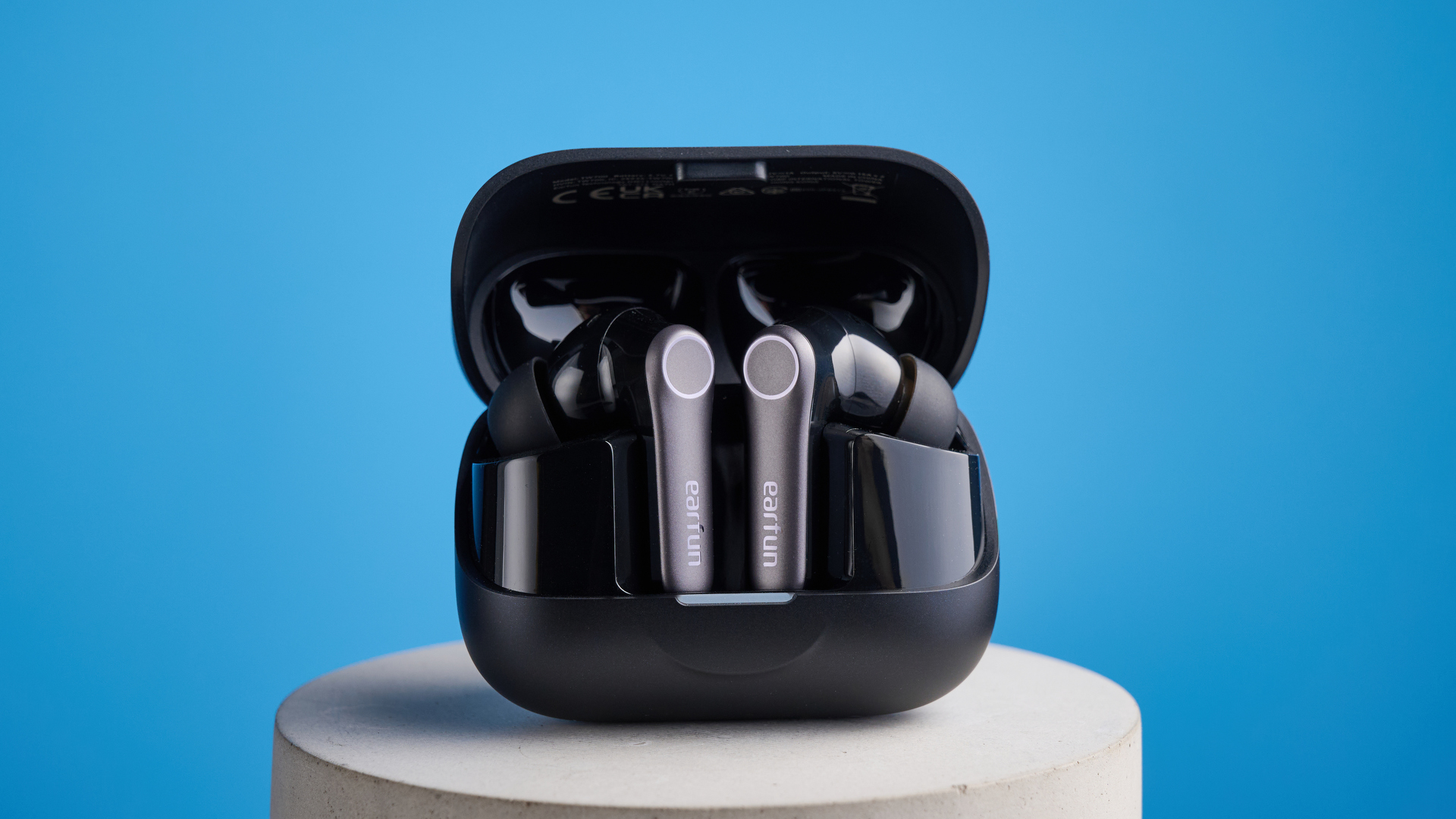 the earfun air pro 4+ earbuds in black showing the ear tips, charging case, and being worn