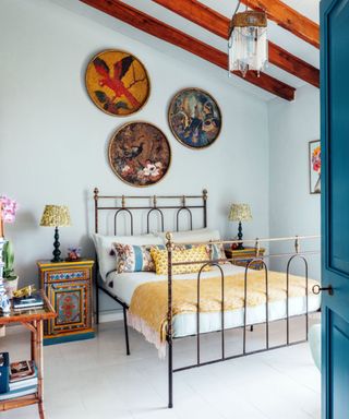 bedroom with light blue walls, wood ceiling beams and eclectic decor