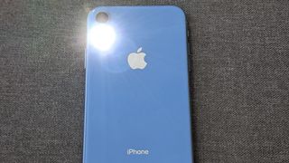 A close-up of an iPhone back with the flashlight on