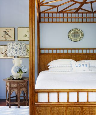 A bedroom furniture idea with warm wood four poster bed, matching bedside table and light blue walls