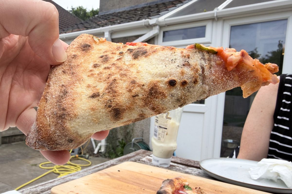 A pizza slice in hand showing the base