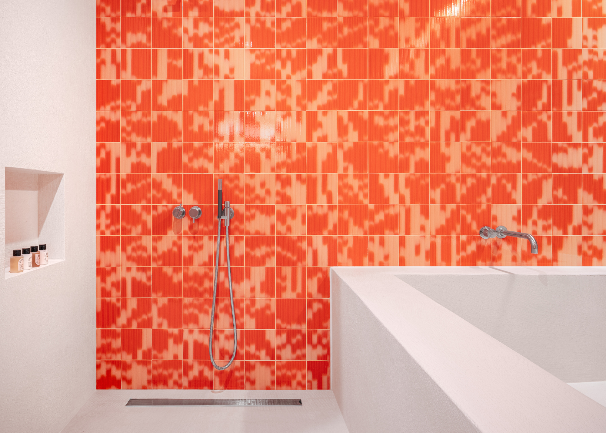 orange and red tones palet tiles coat the wall of a minimalistic bathroom