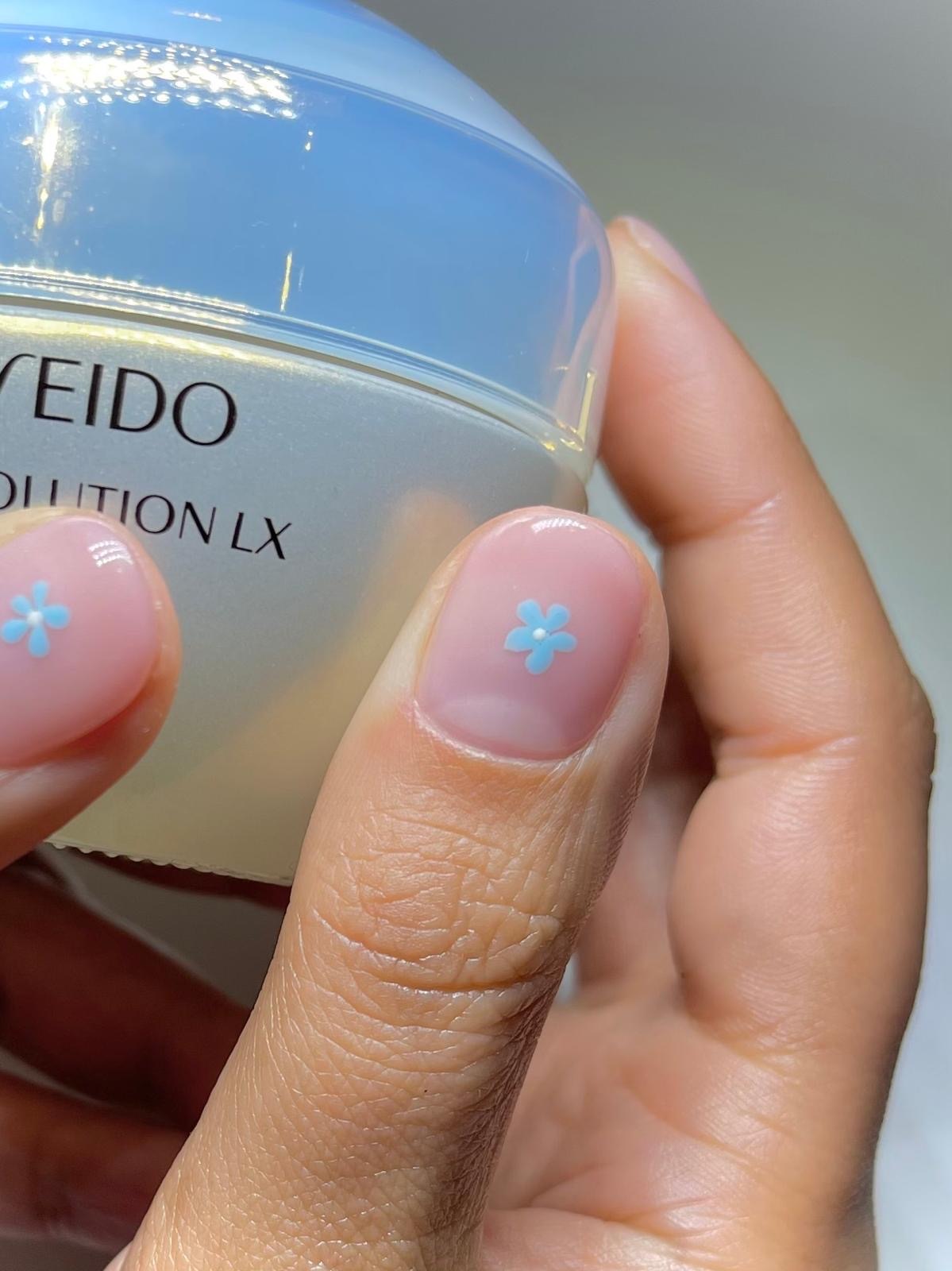 A close-up of Harriet Westmoreland's milky manicure, featuring two small blue flower nail art details on the thumbs