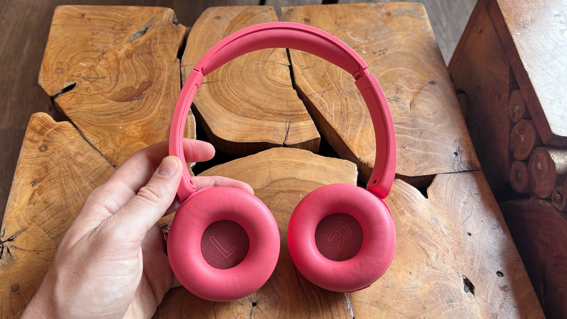 Sony WH-CH530 wireless headphones held in hand over wooden furniture showing inside of earcups
