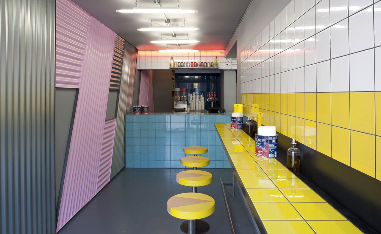 Voodoo Ray’s restaurant with yellow stool, yellow and white tile on wall.