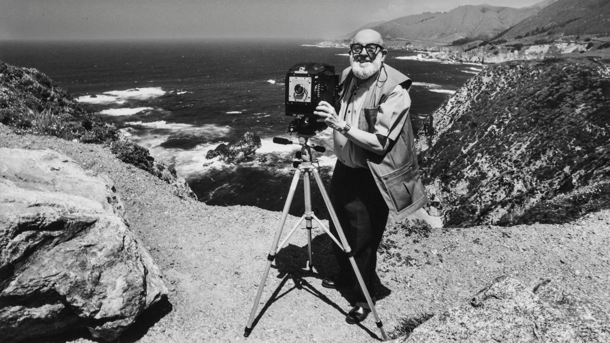 Photographer Ansel Adams stands with a large format camera on a tripod while photographing the Big Sur Coast near Carmel, California. |