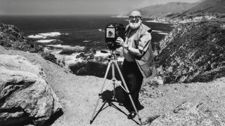Photographer Ansel Adams stands with a large format camera on a tripod while photographing the Big Sur Coast near Carmel, California. |