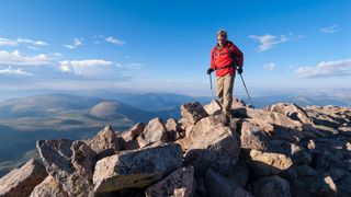 Man very high on mountain summit recreating and taking in views