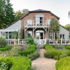 Rear exterior of a converted Victorian building with wooden clad side extensions, a veranda and wooden balcony