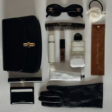 a photo of a woman's bag contents with one of the best wallets for women along with gloves, beauty products, and sunglasses