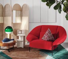 A living room with a bright red couch and green carpet
