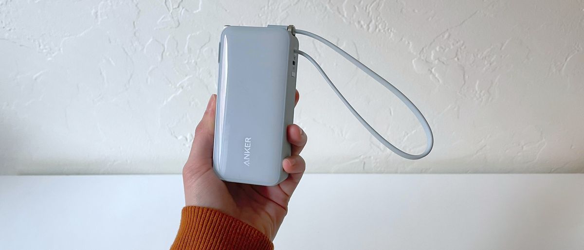 A hand holding the Anker A1637 portable charger in front of a white background