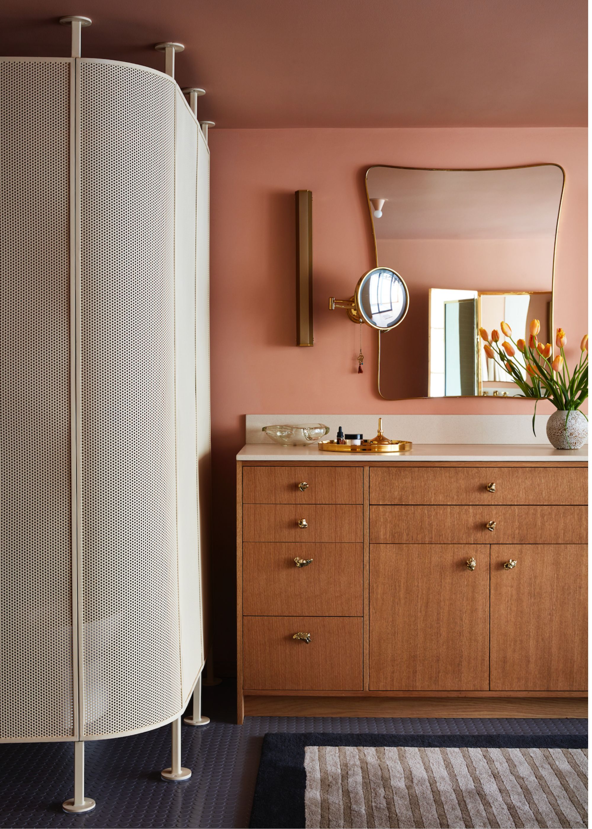 A bathroom with pink painted walls, wooden vanity and a textured bathroom partition