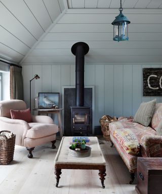 blue living room with log burner and pale pink sofas