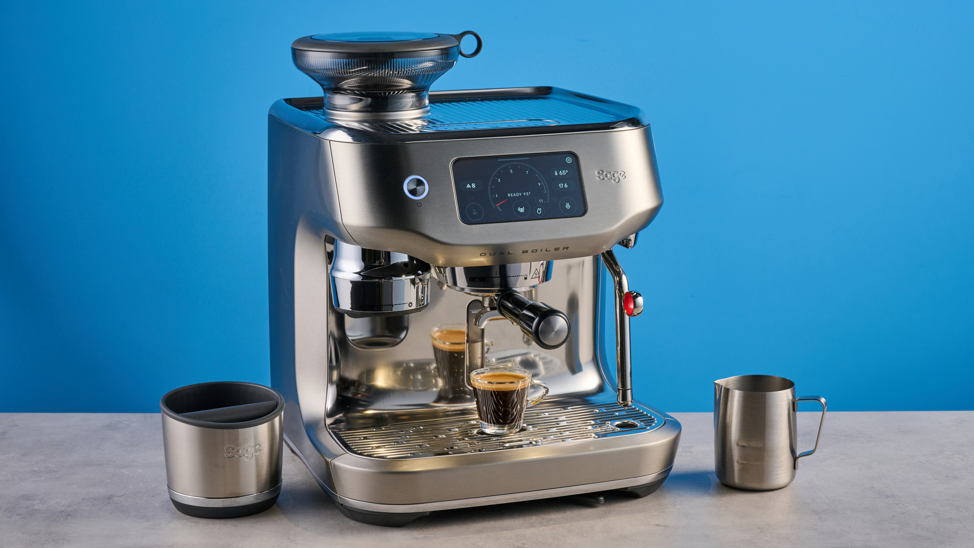 the breville oracle dual boiler / sage oracle dual boiler in stainless steel, showing its touchscreen, steam wand, built in grinder, and espresso shots