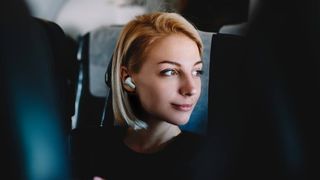 Woman wearing Creative Zen Air earbuds on a plane.