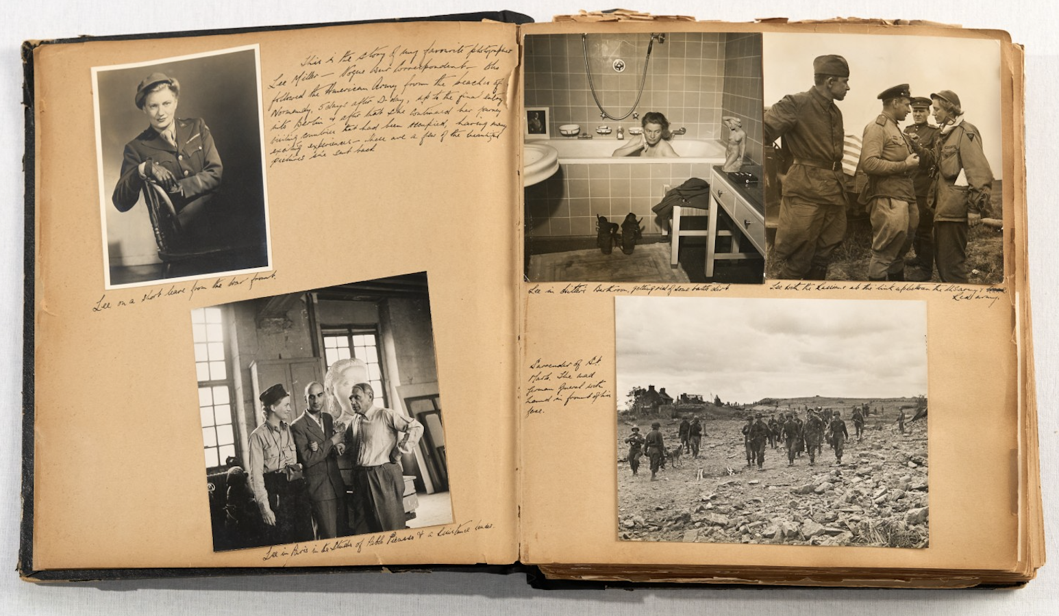 A scrapbook spread showing five black-and-white wartime photographs including a woman in military uniform, a figure bathing in a domestic tub, soldiers in a ruined landscape, two men on their knees before a wall, and a group of figures in a sunlit studio.
