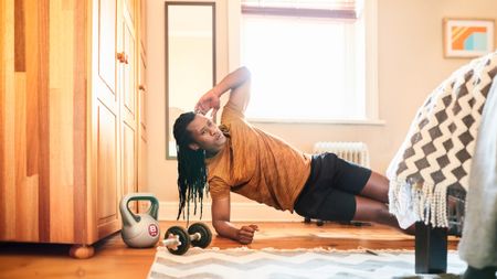 Shot of a muscular man doing sideways planks at home