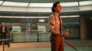 Loki holds a watch and TVA prune stick as he looks at the Temporal Loom in Loki season 2