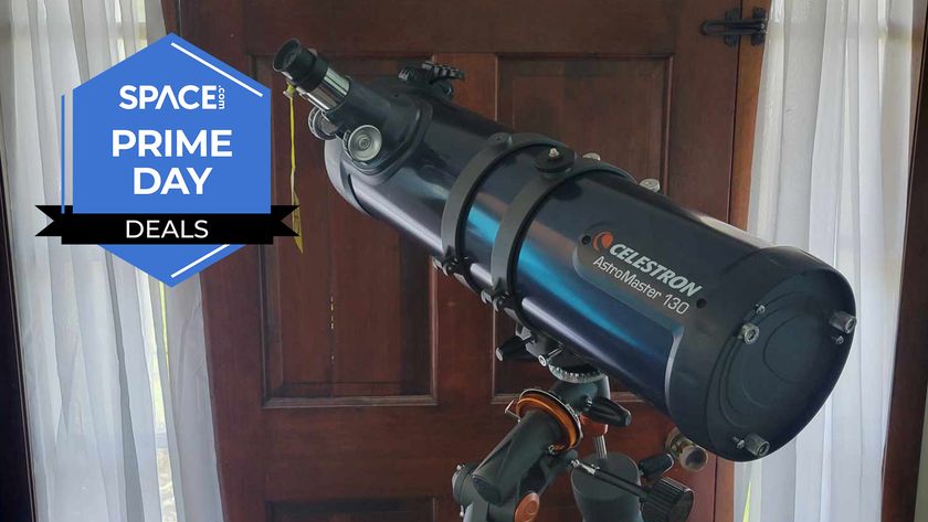 A Celestron Astromaster 130EQ telescope in front of a brown door, with a Space Prime Day deals logo. 