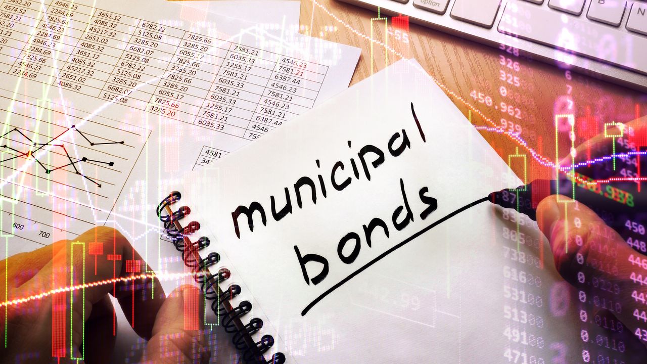 The words&quot; municipal bonds&quot; written in a spiral notebook sitting on top of investing charts.