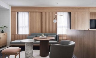 Kimpton Da An hotel lounge with grey sofa and tub chair, round marble and wood tables and pale timber wall panelling
