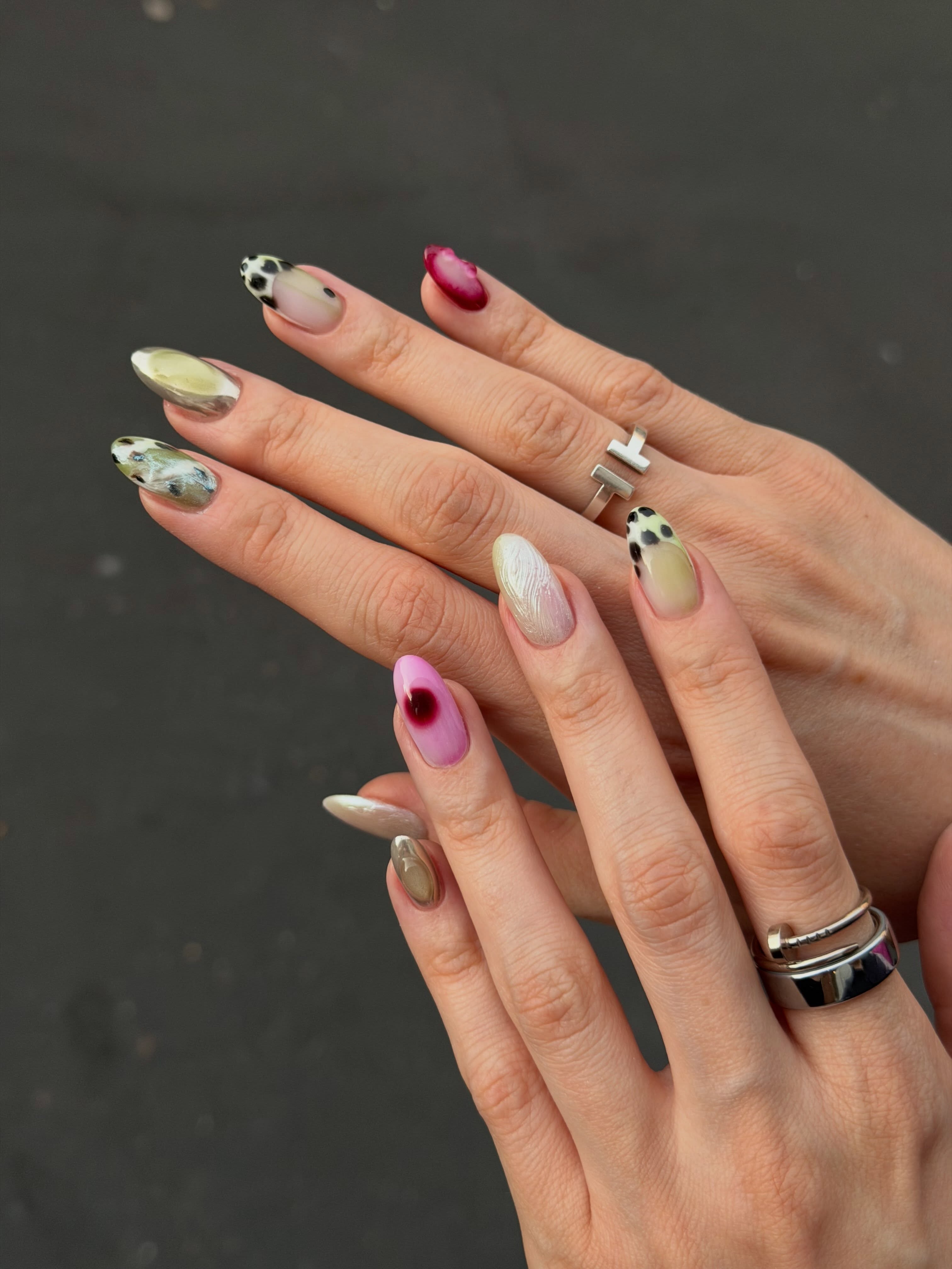 An image of mismatched green, pink, and white nails.
