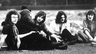 King Crimson’s original line-up posing for a photograph while sitting in a field in 1969