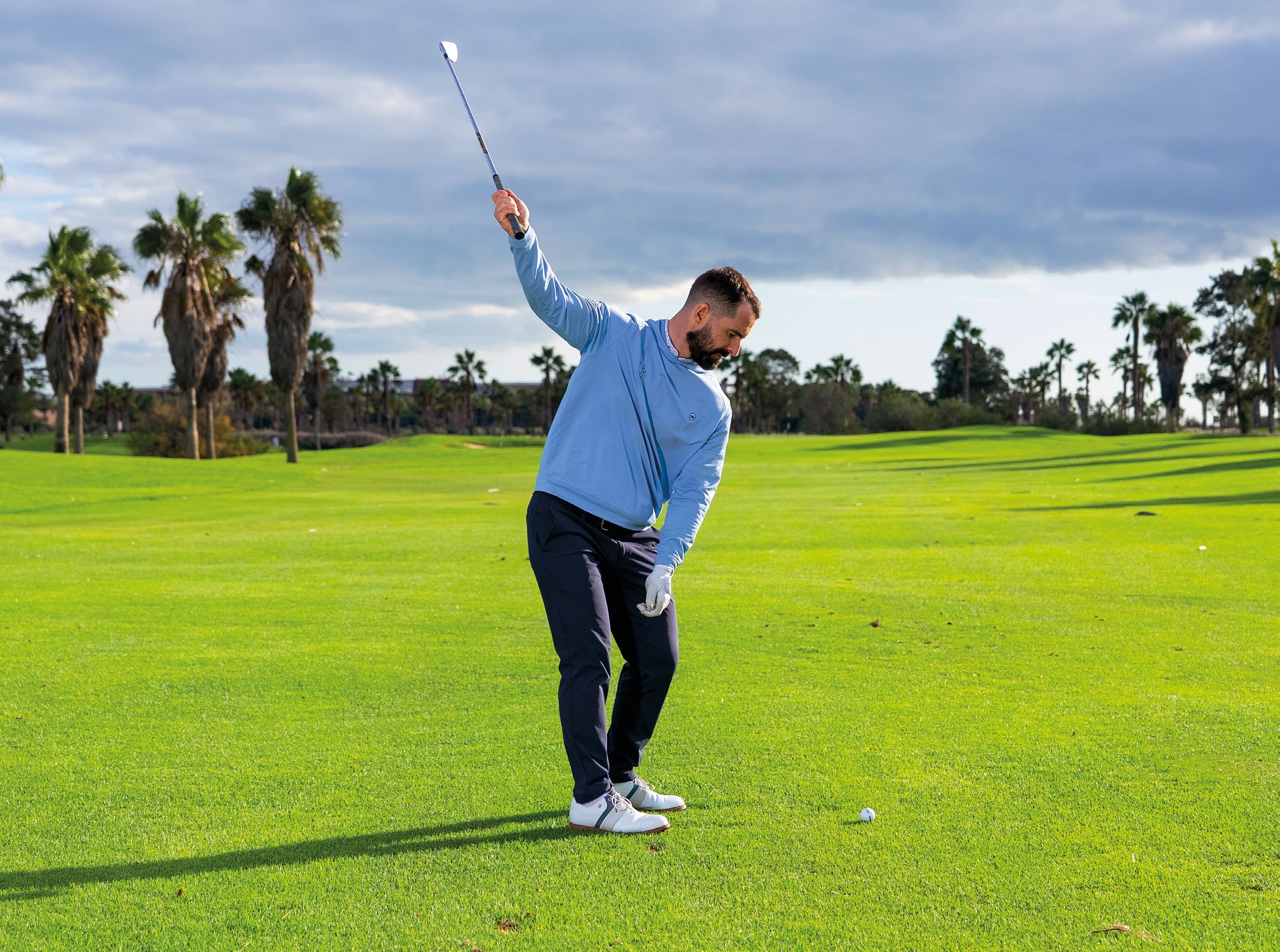 James Jankowski demonstrating how to do the one-handed ball striking drill, with the club at the top of the backswing