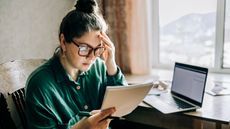 Stressed mid adult woman with laptop reading notes