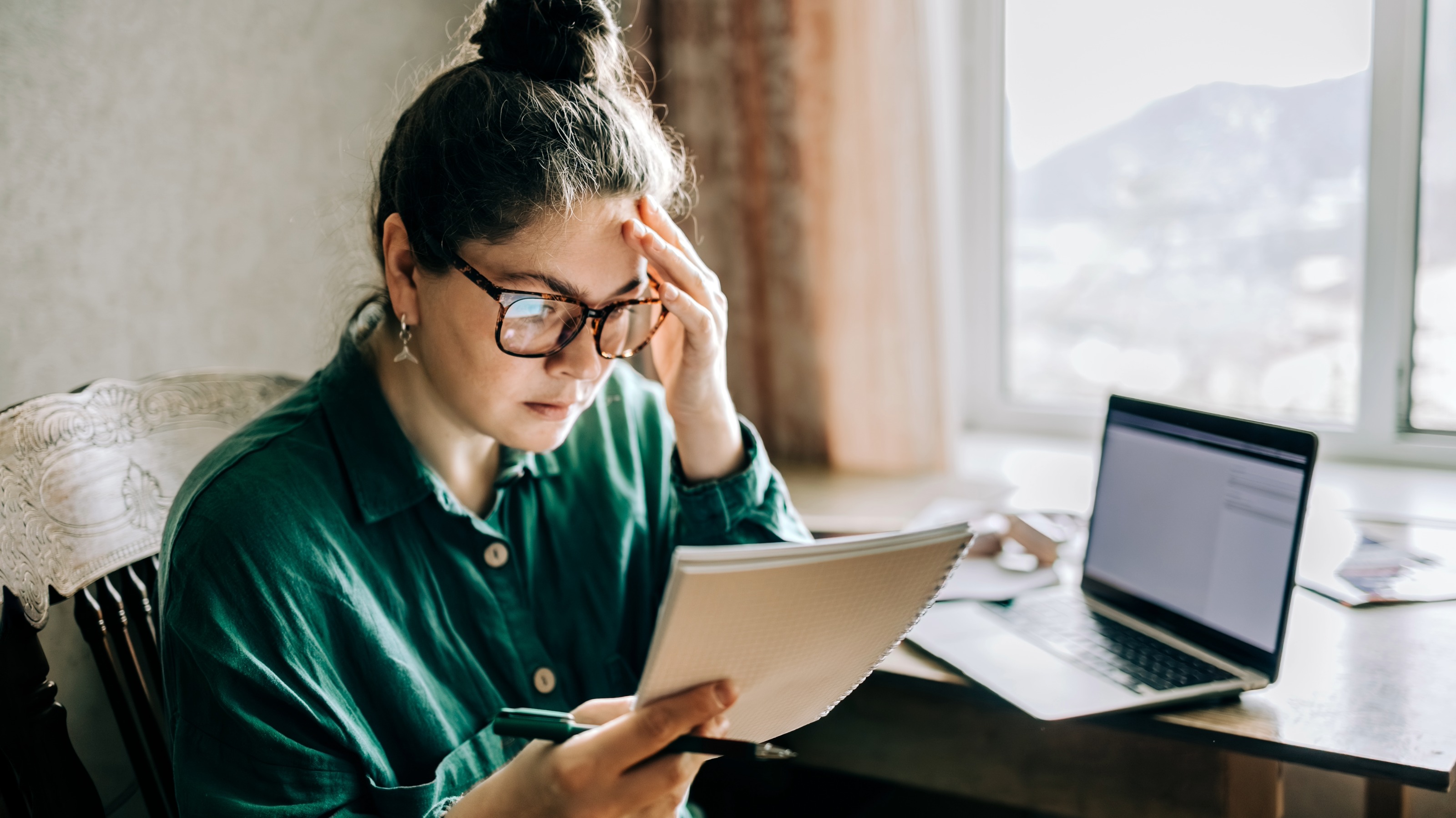 Stressed mid adult woman with laptop reading notes