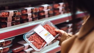 Person holding beef mince packet in supermarket