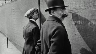 Two men stood against a canvas fence