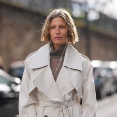 Woman during paris fashion week wearing a trench coat with a blonde wavy bob