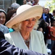 Queen Camilla wears a straw hat as she poses for a selfie with a royal fan during Australia tour