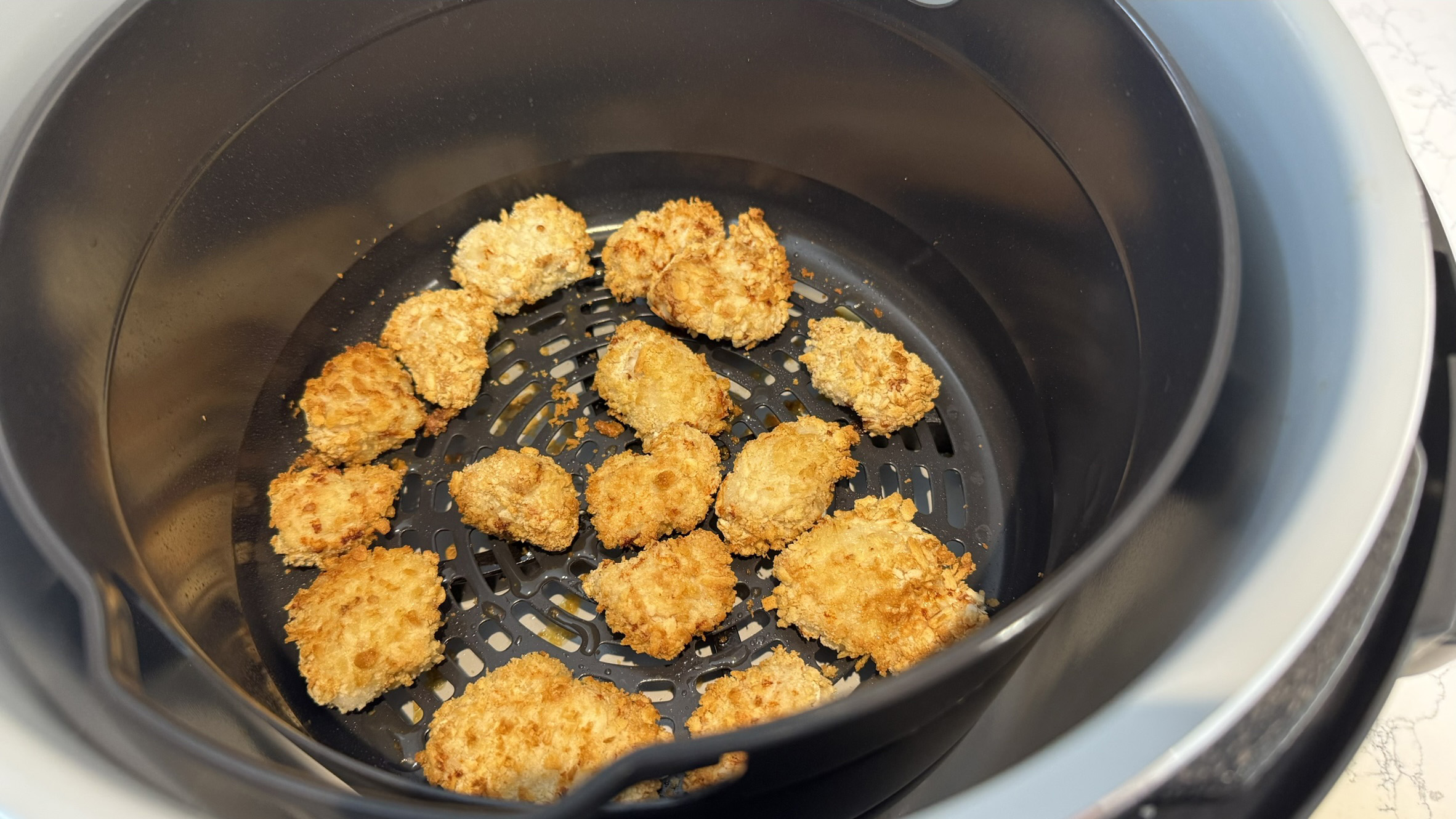 Air fryer sesame chicken in fryer basket