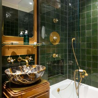 Bathroom with bottle green tiles, bronze fittings and stone sink