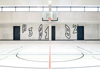 An otherwise normal sports hall is brought to life with L2M3's bold wayfinding markings, inspired by jersey numbers