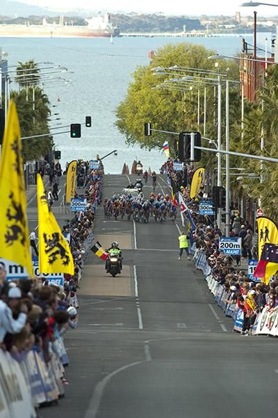 The peloton commences its charge up the home straight to the finish in Geelong with Corio Bay in the background.