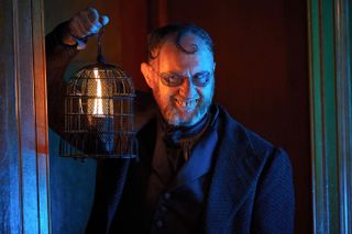 Mr Wickens (Mark Gatiss) appears in a doorway, bearing a candle aloft, a horrible smirk on his face and his yellow teeth on display