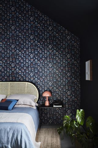 A bedroom with blue painted wall, dark wallpaper and blue bedding