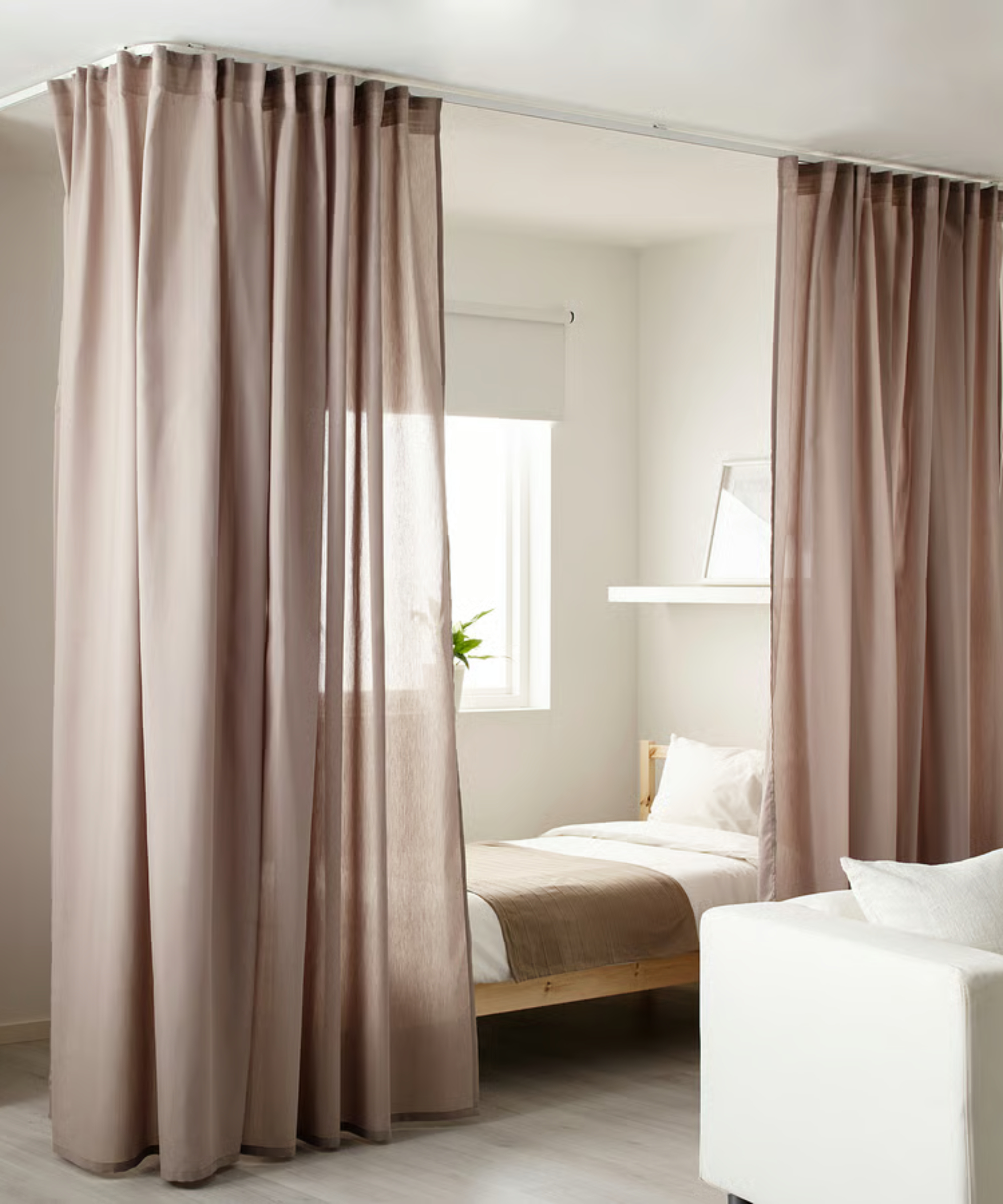bed screened with pink curtains using ceiling mounted curtain track around bed