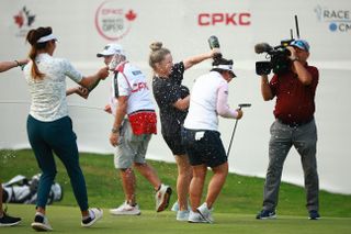 Megan Khang and her caddie get sprayed with champagne on the 18th green