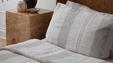 striped linen bedding on a bed with a burl side table